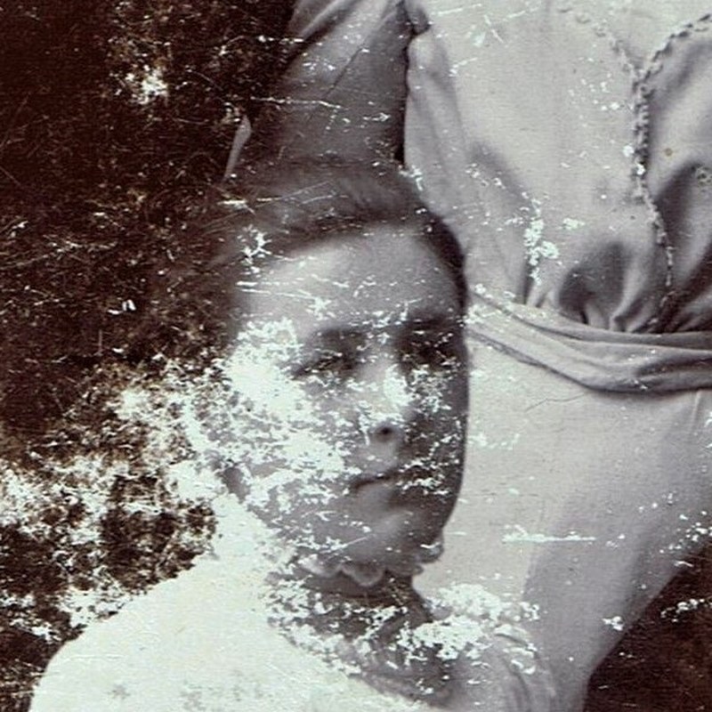 The original: white flaking covers most of her face; a nose, a mouth and the shadow of two eyes show through